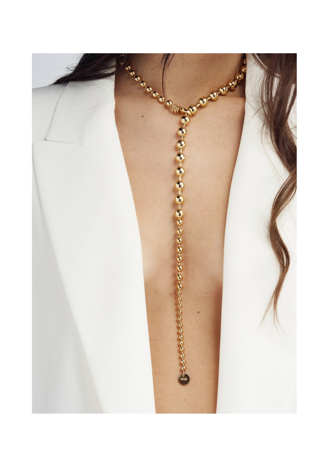 Una collana a sfere in tono oro, indossata con un blazer bianco